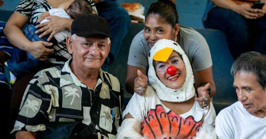 Grandfather smiling with a clown in a chicken costume