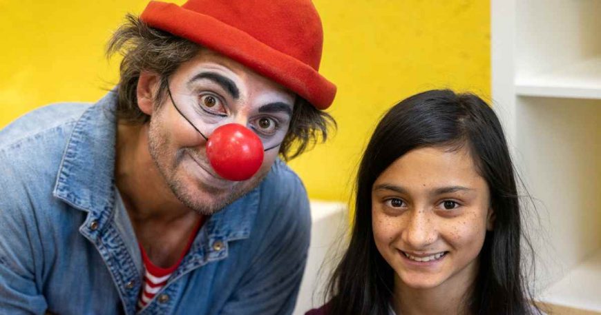 Man in clown attire smiling next to a smiling child
