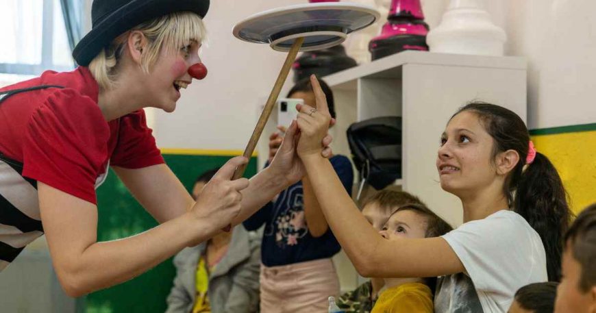 Clown showing a child a plate balancing trick