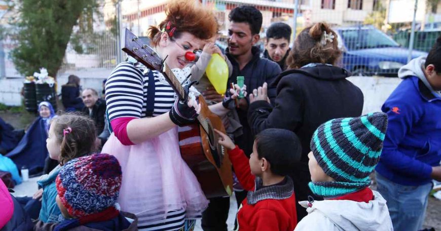 Clowns Without Borders artist Kolleen Kintz shares her guitar with a boy in Lesvos, Greece 2016.