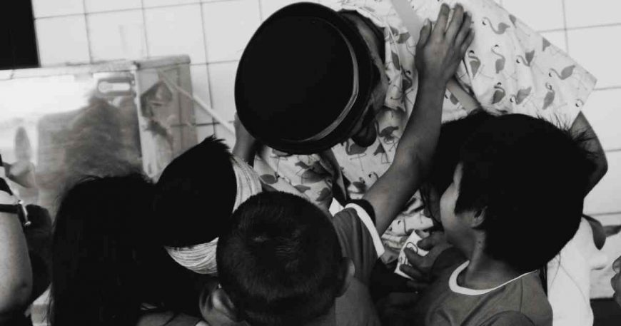 CWB artist bends to hug kids at a clown show in Brazil