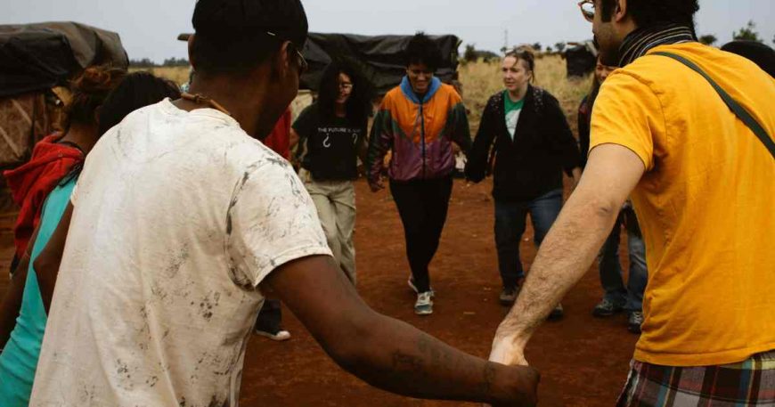 CWB artists hold hands and dance with the Guarani as a welcome to the community