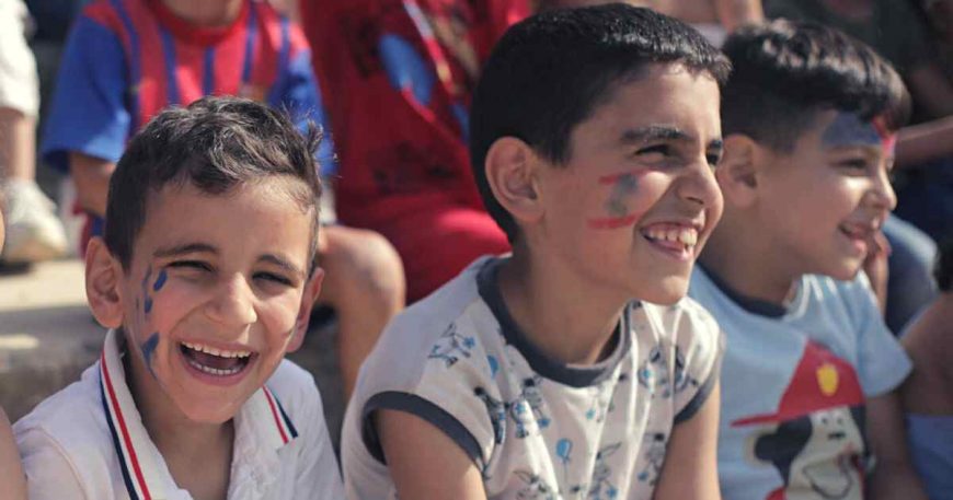 Two elementary aged boys laugh at a clown show in Lebanon.
