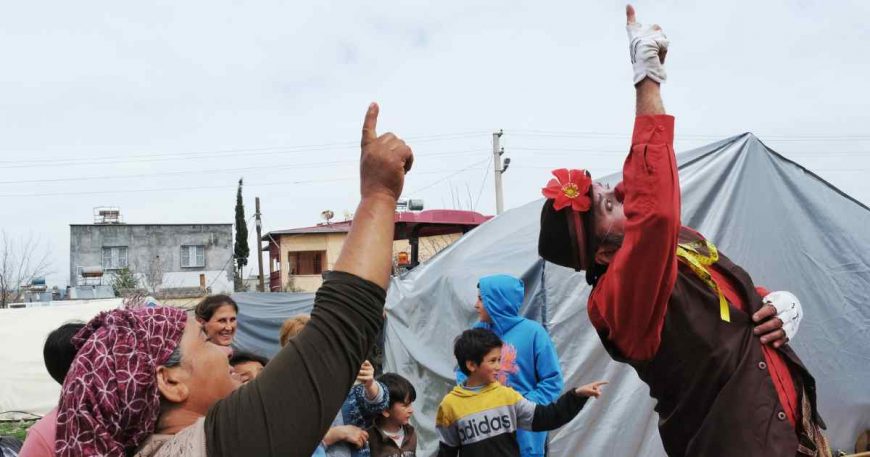 A clown points to the sky and gets an older woman to do the same at a clown show for earthquake survivors in Turkey.