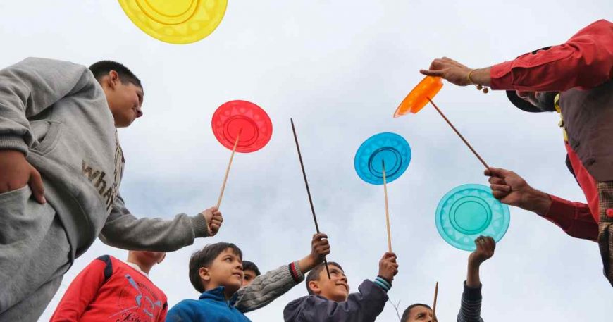 Clowns in Turkey play with kid survivors of the earthquake, teaching them to balance plates on a stick.