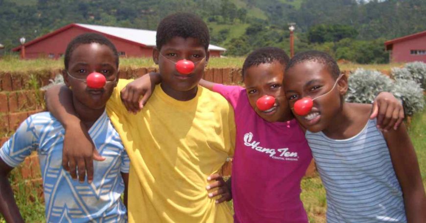 Four kids pose for the camera with red clown noses.