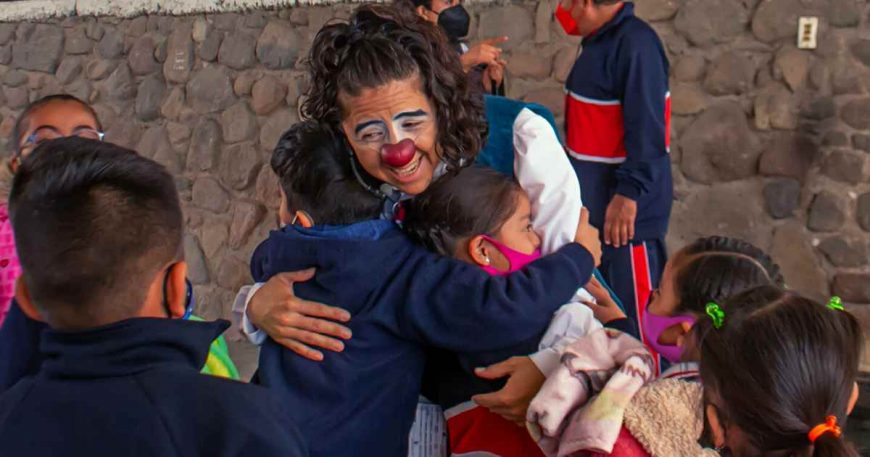 Vanessa hugs a two children at the end of the clown show, demonstrating how play helps connect