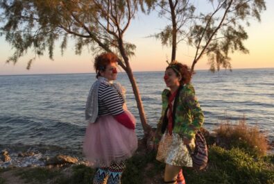 Women clowns by the water smiling