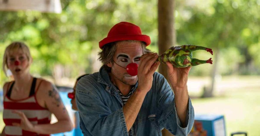 A clown in Puerto Rico looks 'through' a rubber chicken, serving as his scope.
