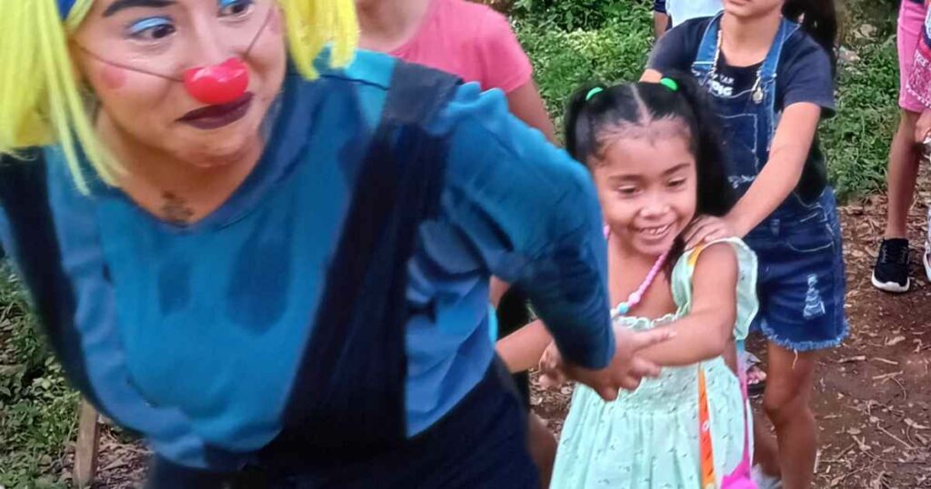 A clown plays train with kids in El Salvador