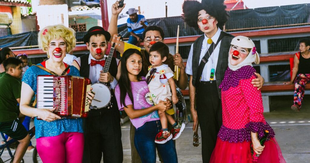 Five clowns pose with a girl and her baby brother after a clown show.